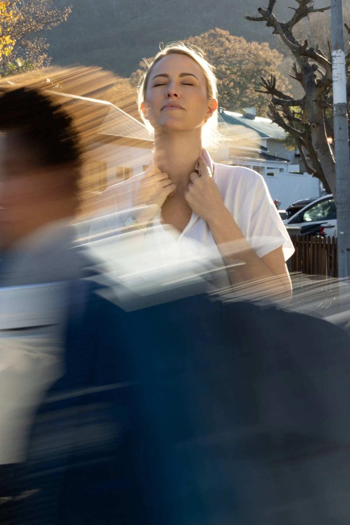 A woman using the cooling cloth as people pass by